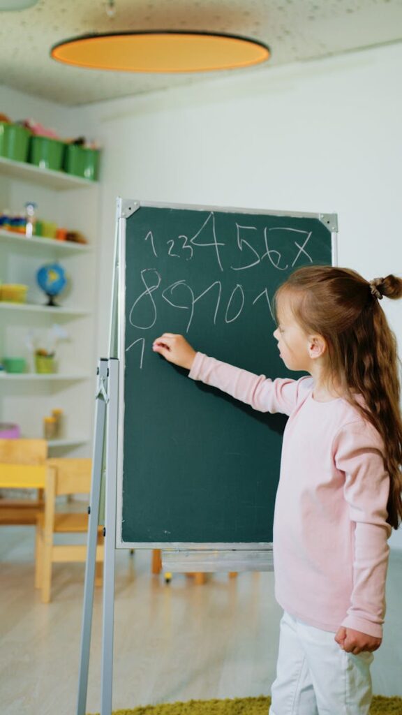 pexels-photo-8088233 A girl engaging in educational learning by writing numbers on a chalkboard in a classroom.