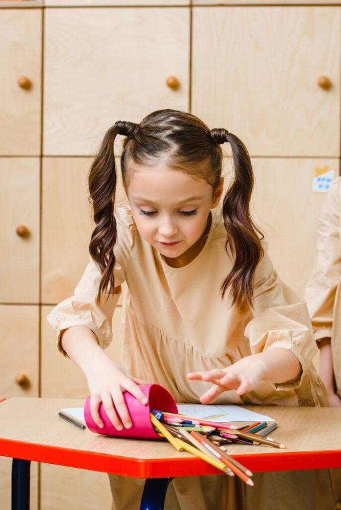 pexels-photo-8466712 Young girl with ponytails organizing pencils from a pink holder on a school desk.